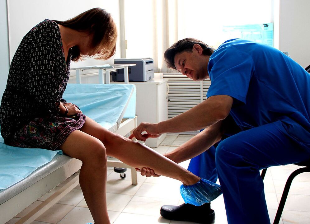 doctor examines legs with varicose veins